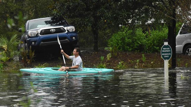 A man paddles through the neighborhood as Hurricane Florence leaves a trail of flooded roads, broken trees and downed power lines across Leland, N.C., Sunday, Sept. 16, 2018. (Ken Blevins/The Star-News via AP)